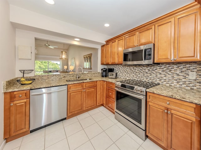kitchen with brown cabinetry, stainless steel appliances, tasteful backsplash, and a sink