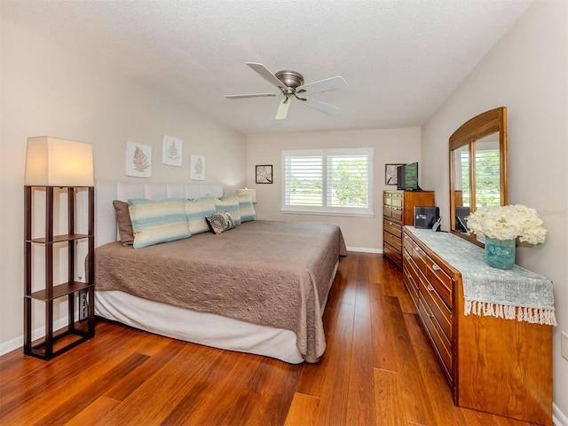 bedroom with baseboards, dark wood-type flooring, a ceiling fan, and multiple windows