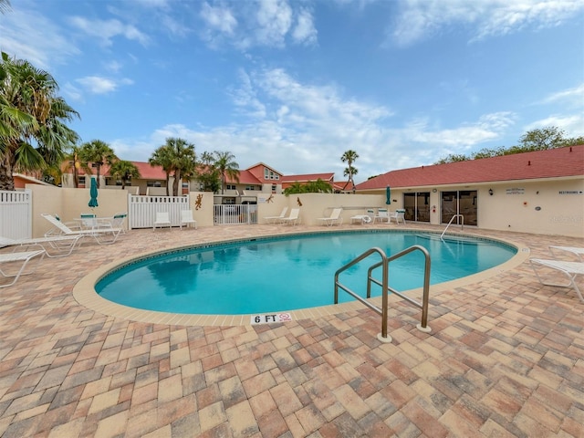 community pool with fence and a patio