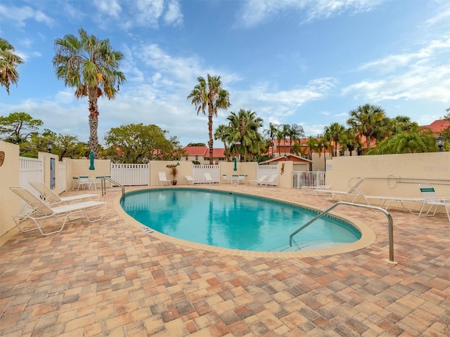 pool with a patio area and fence