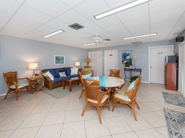 dining space with visible vents, a ceiling fan, light tile patterned floors, a drop ceiling, and baseboards