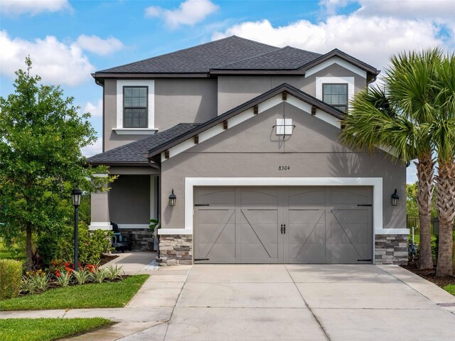 8304 Shooting Star Rd, Sarasota, FL 34241 - view of front of home featuring stone siding, driveway, stucco siding, a shingled roof, and an attached garage