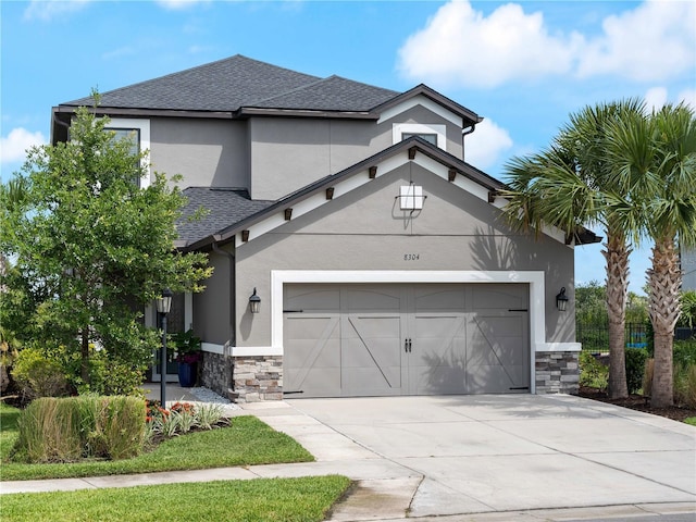 8304 Shooting Star Rd, Sarasota, FL 34241 - view of front facade with stone siding, an attached garage, stucco siding, roof with shingles, and driveway