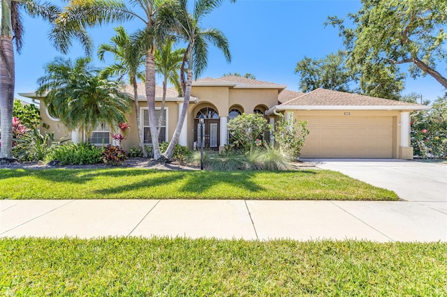 mediterranean / spanish-style house featuring a garage, stucco siding, driveway, and a front yard