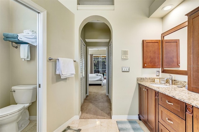 ensuite bathroom featuring toilet, baseboards, ensuite bathroom, and vanity