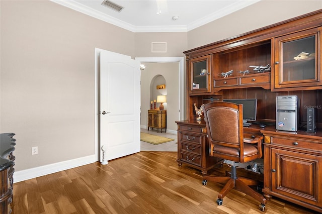 office with arched walkways, ornamental molding, wood finished floors, and visible vents