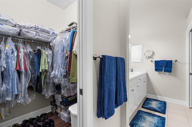 bathroom featuring baseboards, a spacious closet, tile patterned flooring, and vanity