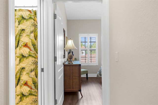 hallway featuring baseboards and wood finished floors