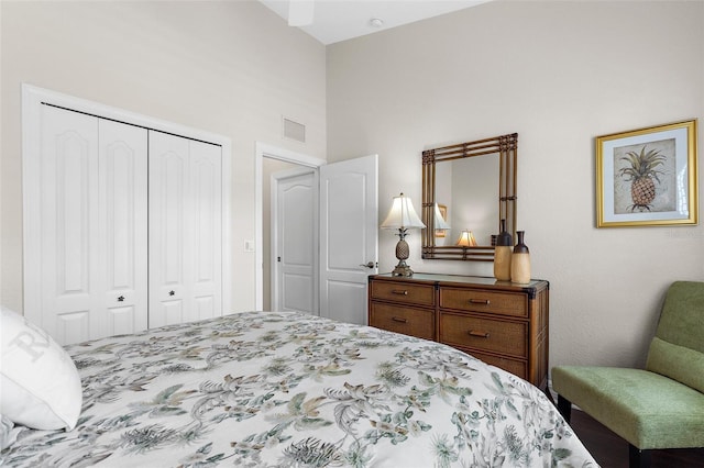 bedroom with visible vents, a high ceiling, and a closet