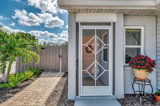 entrance to property featuring fence, a gate, and stucco siding