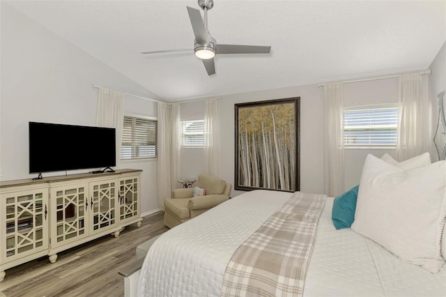 bedroom with a ceiling fan, wood finished floors, and vaulted ceiling