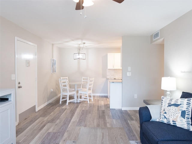 living area featuring ceiling fan, visible vents, baseboards, and light wood-type flooring