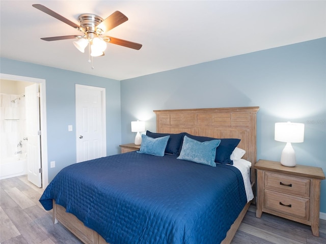 bedroom with baseboards, ceiling fan, ensuite bathroom, and wood finished floors