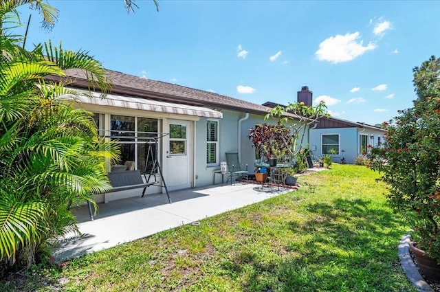 657 Foxwood Blvd, Englewood, FL 34223 - rear view of house featuring a chimney, a yard, a patio, and stucco siding