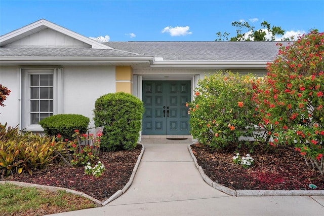 property entrance with an attached garage, a shingled roof, and stucco siding