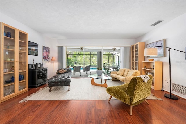 living area with a sunroom, visible vents, and wood finished floors