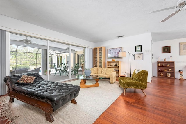 living area with ceiling fan, visible vents, and wood finished floors