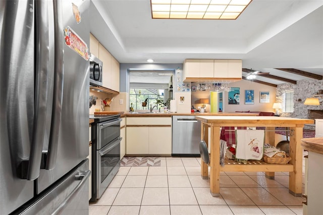 kitchen featuring cream cabinetry, appliances with stainless steel finishes, and light tile patterned flooring