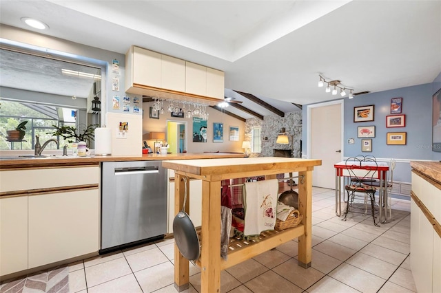 kitchen featuring a fireplace, white cabinets, light tile patterned flooring, and stainless steel dishwasher