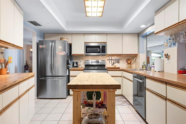 kitchen featuring a sink, visible vents, light tile patterned floors, wooden counters, and appliances with stainless steel finishes