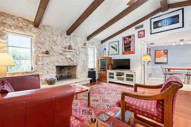 living area with visible vents, wood finished floors, lofted ceiling with beams, and a fireplace