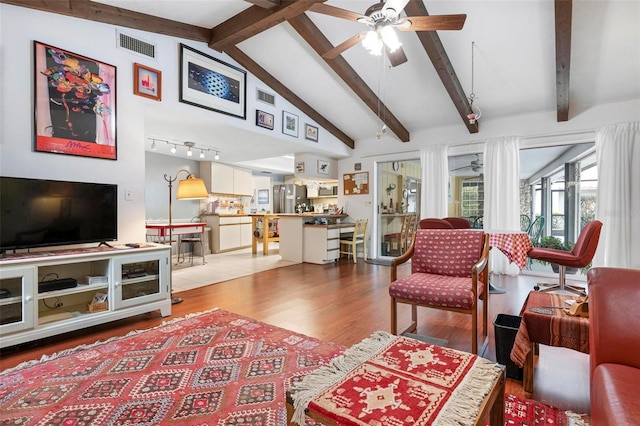 living room featuring ceiling fan, wood finished floors, visible vents, and vaulted ceiling with beams
