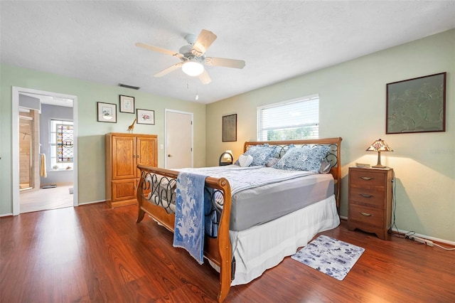 bedroom with baseboards, ceiling fan, visible vents, connected bathroom, and wood finished floors