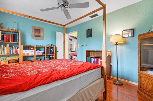 bedroom with baseboards, visible vents, and wood finished floors