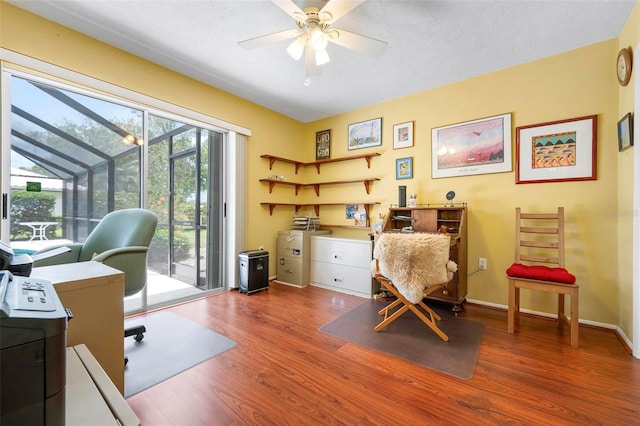office area featuring a ceiling fan, baseboards, a sunroom, and wood finished floors