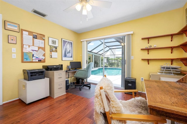 office space featuring baseboards, visible vents, ceiling fan, a sunroom, and wood finished floors