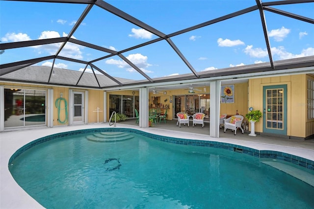 pool featuring a patio, a ceiling fan, and glass enclosure