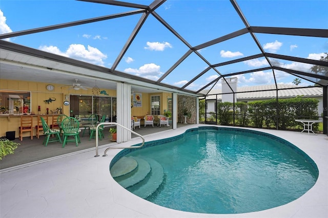 outdoor pool with a ceiling fan, glass enclosure, and a patio