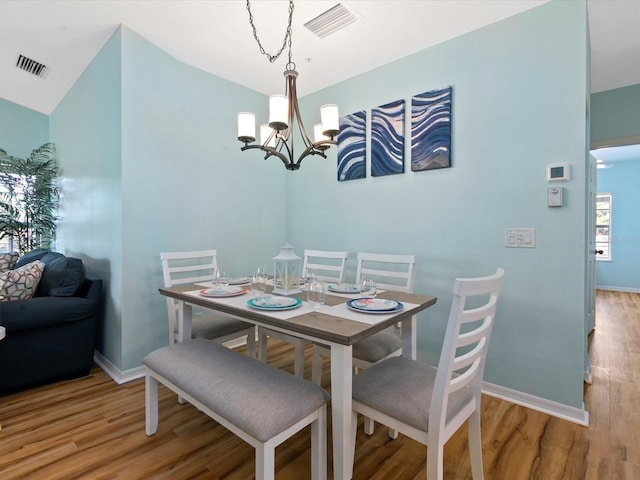 dining area with an inviting chandelier, wood finished floors, and visible vents