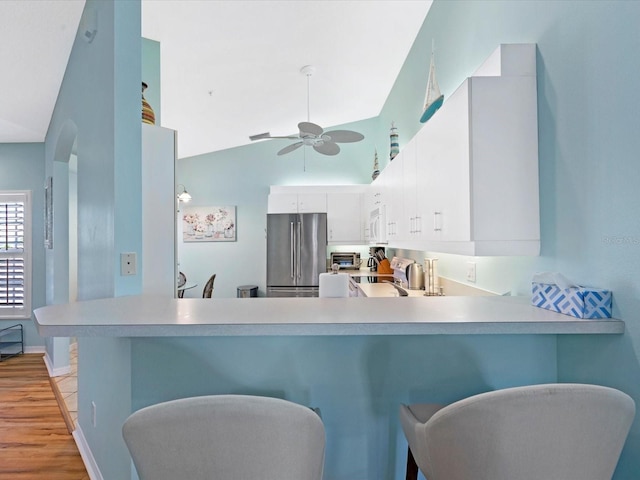 kitchen featuring ceiling fan, range with electric stovetop, freestanding refrigerator, white microwave, and a peninsula