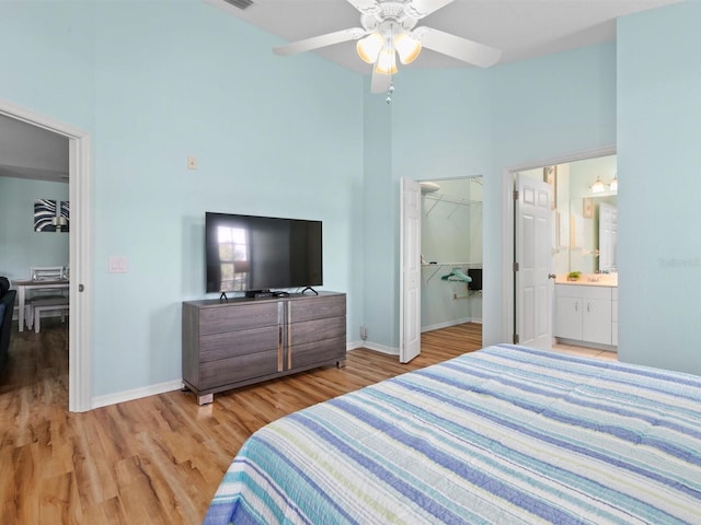 bedroom with baseboards, a high ceiling, a walk in closet, and light wood finished floors