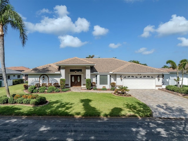 314 Oakwood Cir, Englewood, FL 34223 - view of front facade featuring a tile roof, a garage, stucco siding, a front lawn, and decorative driveway