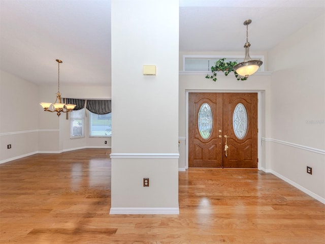 314 Oakwood Cir, Englewood, FL 34223 - entrance foyer with baseboards, light wood-style floors, and an inviting chandelier