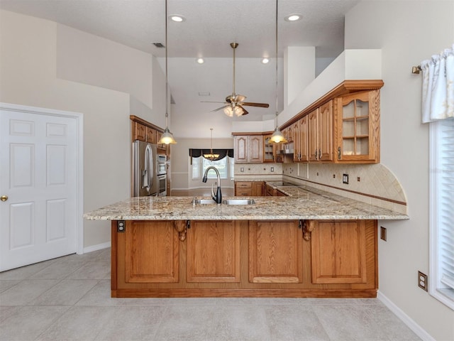 314 Oakwood Cir, Englewood, FL 34223 - kitchen featuring brown cabinetry, light stone counters, ceiling fan, a sink, and stainless steel refrigerator with ice dispenser