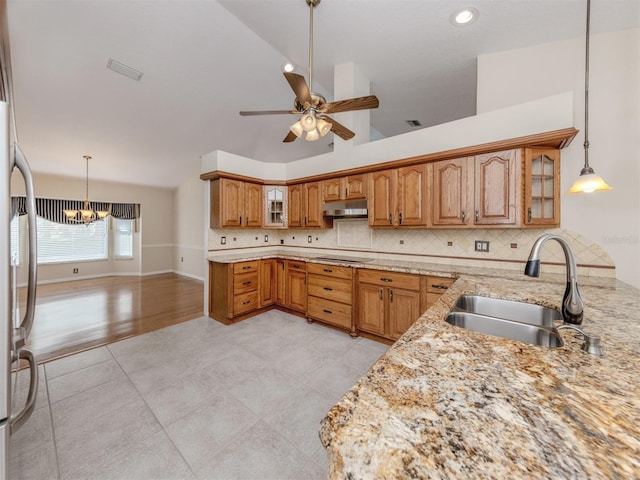 314 Oakwood Cir, Englewood, FL 34223 - kitchen featuring brown cabinets, a sink, under cabinet range hood, lofted ceiling, and black electric stovetop