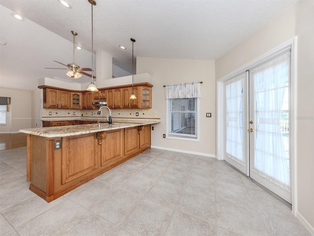 314 Oakwood Cir, Englewood, FL 34223 - kitchen with a peninsula, glass insert cabinets, brown cabinets, a sink, and vaulted ceiling