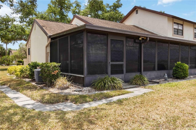5559 Brassy Loop, North Port, FL 34287 - view of home's exterior featuring a sunroom, a shingled roof, stucco siding, and a yard