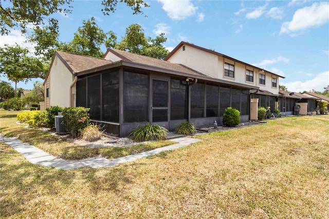 5559 Brassy Loop, North Port, FL 34287 - rear view of house featuring a sunroom, a lawn, stucco siding, and central AC unit