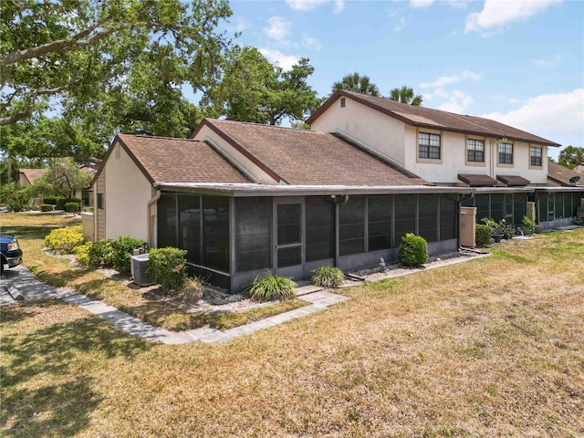 5559 Brassy Loop, North Port, FL 34287 - back of house with a sunroom, stucco siding, a shingled roof, and a lawn