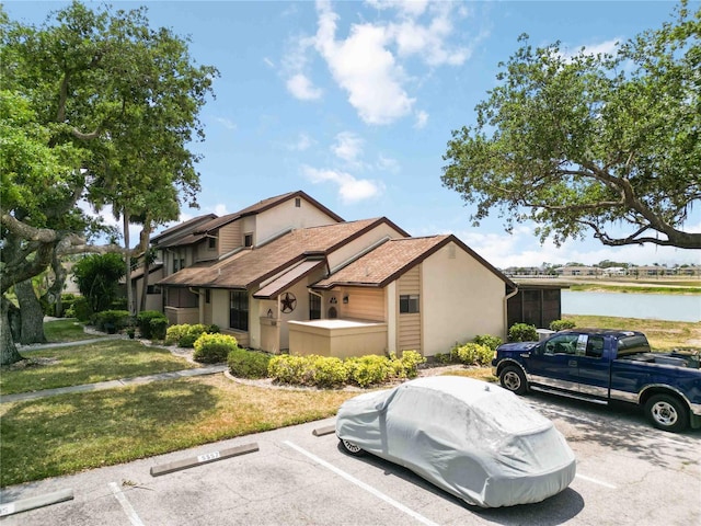 5559 Brassy Loop, North Port, FL 34287 - view of front of property featuring uncovered parking, stucco siding, a water view, and a front lawn