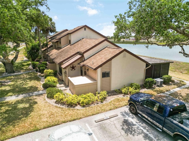 5559 Brassy Loop, North Port, FL 34287 - view of side of property with a water view, a shingled roof, uncovered parking, a lawn, and stucco siding