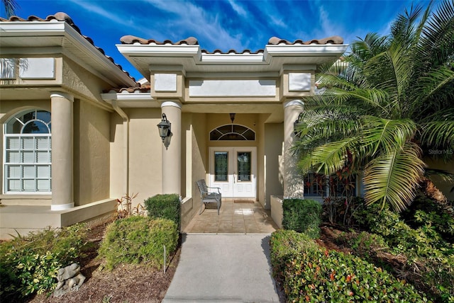 doorway to property with a tiled roof, french doors, and stucco siding