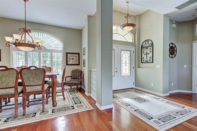 entryway with baseboards, a towering ceiling, wood finished floors, and a notable chandelier