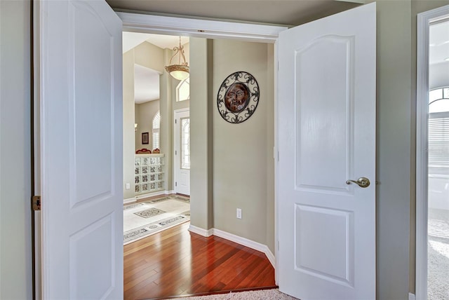 corridor featuring baseboards and wood finished floors