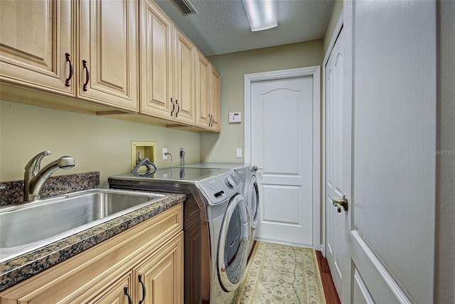 laundry room featuring a textured ceiling, independent washer and dryer, visible vents, cabinet space, and a sink