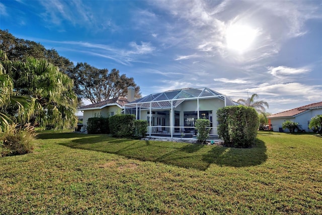 back of house with a yard, stucco siding, and glass enclosure